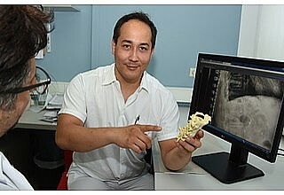 Bastian Himpe zeigt an einem Modell, an welchen Teilen der Wirbelsäule Implantate eingesetzt werden können. (Foto: Elke Lindner/Uniklinik)