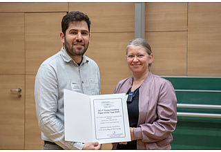 Dr. rer. nat. Konstantinos Katsoulis-Dimitriou ist der Gewinner des „GC-I3 Paper of the Year: Young Research Award“. Vergeben wurde der Preis durch Prof. Dr. Dr. Anne Albrecht, Prodekanin für Nachwuchsentwicklung und Chancengleichheit, im Rahmen des diesjährigen Young Research Day der Medizinischen Fakultät Magdeburg am 18. Mai 2026. Fotografin: Melitta Schubert/Universitätsmedizin Magdeburg